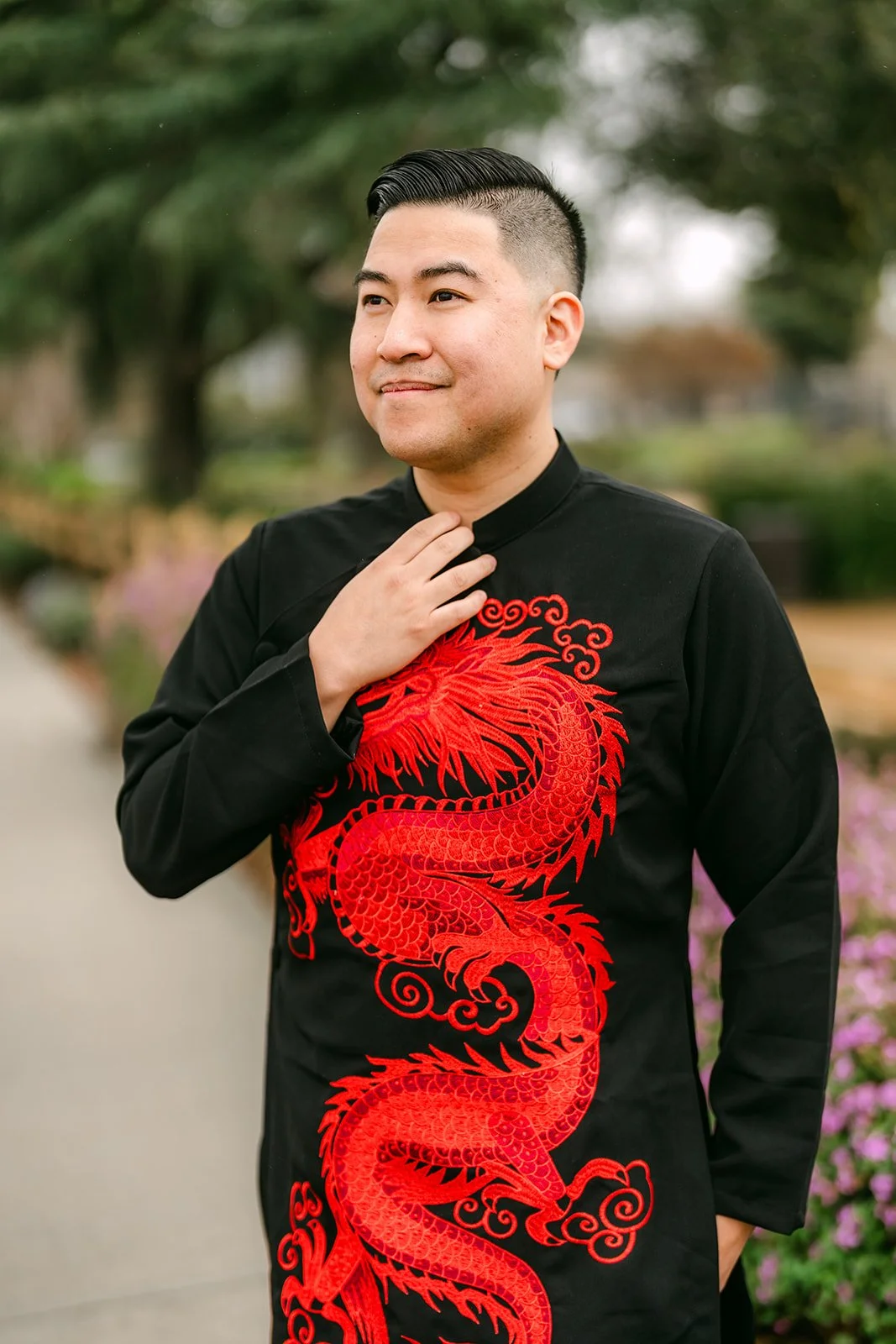 A groom smiling and straightening the collar of his black and red dragon changshan.