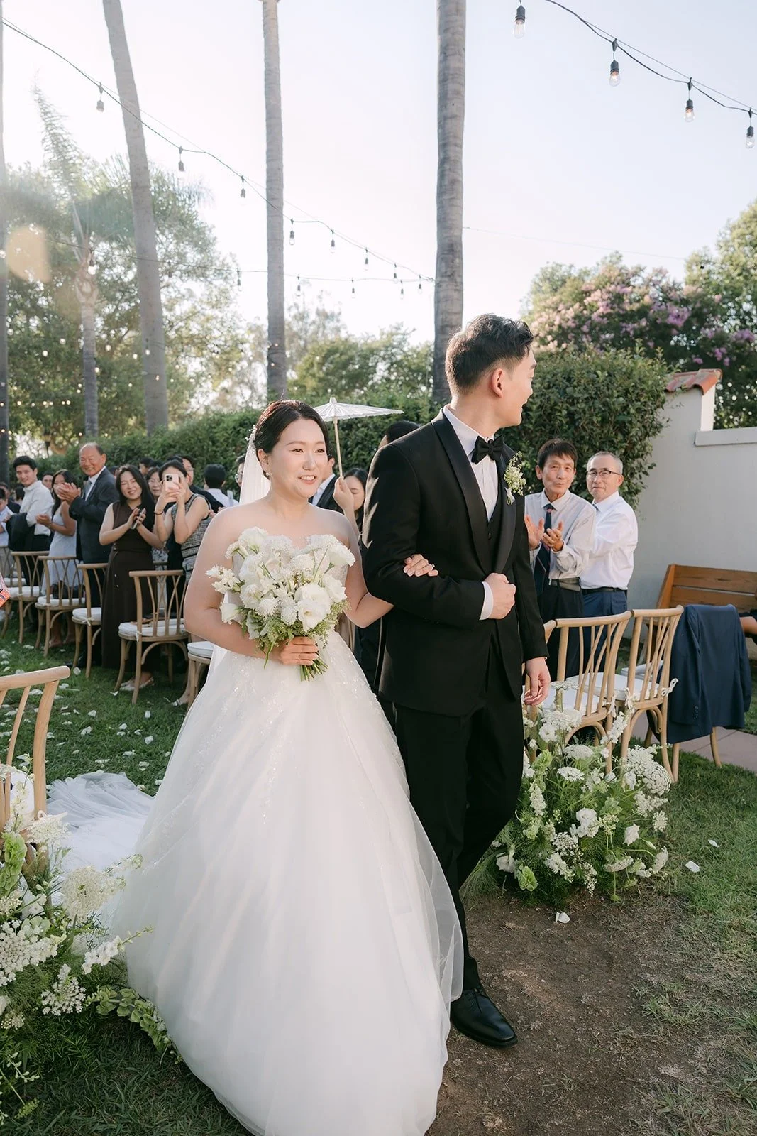 Amy and Sam smiling as guests cheer, photographed by One and Only Production