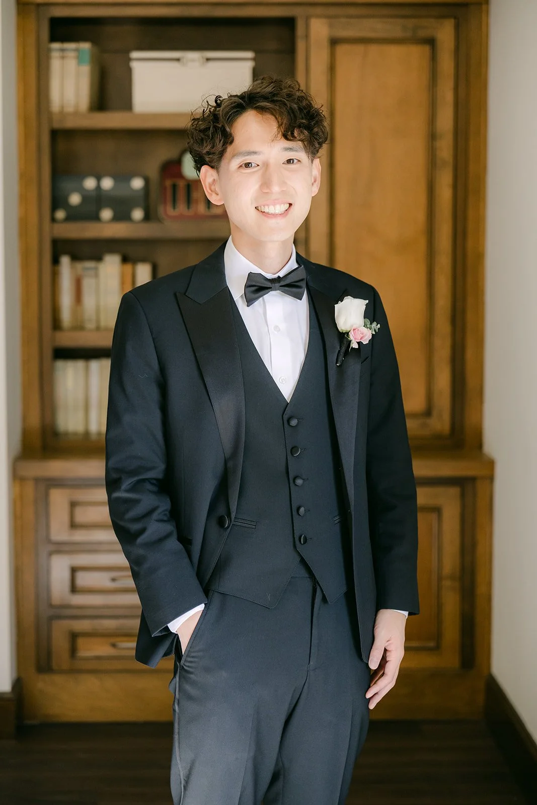 Tony in a black tuxedo and bow tie standing in the groom's suite