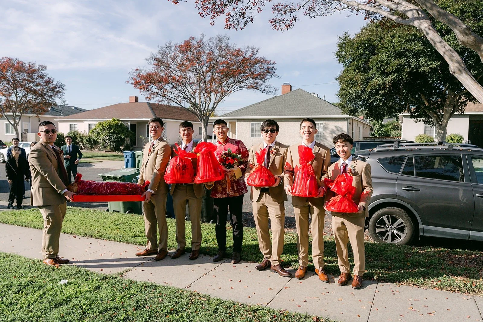 Groomsmen line up outside Shayna's family home with red gift boxes for the door game