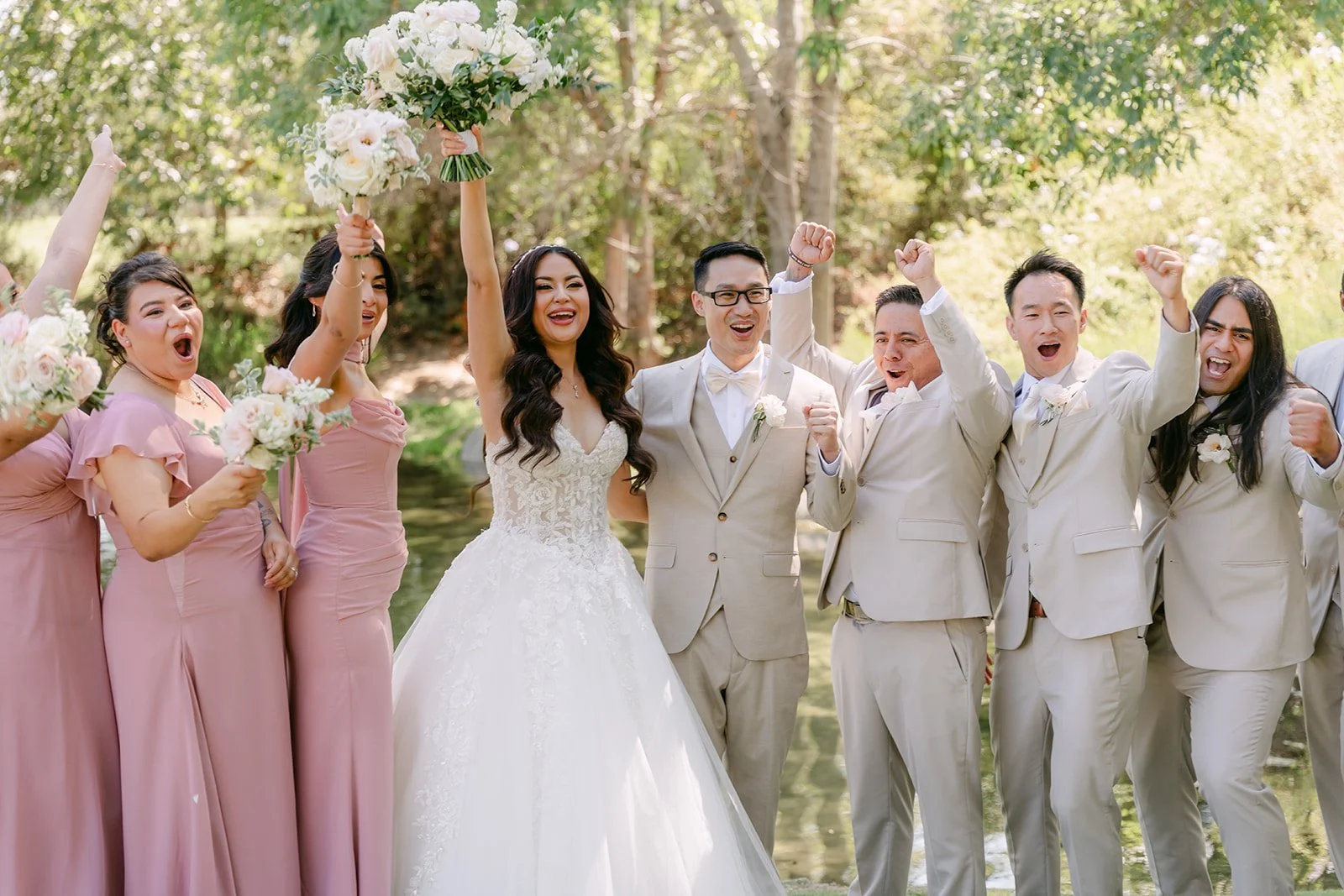 The wedding party cheering with bouquets raised at Coyote Hills Golf Course.
