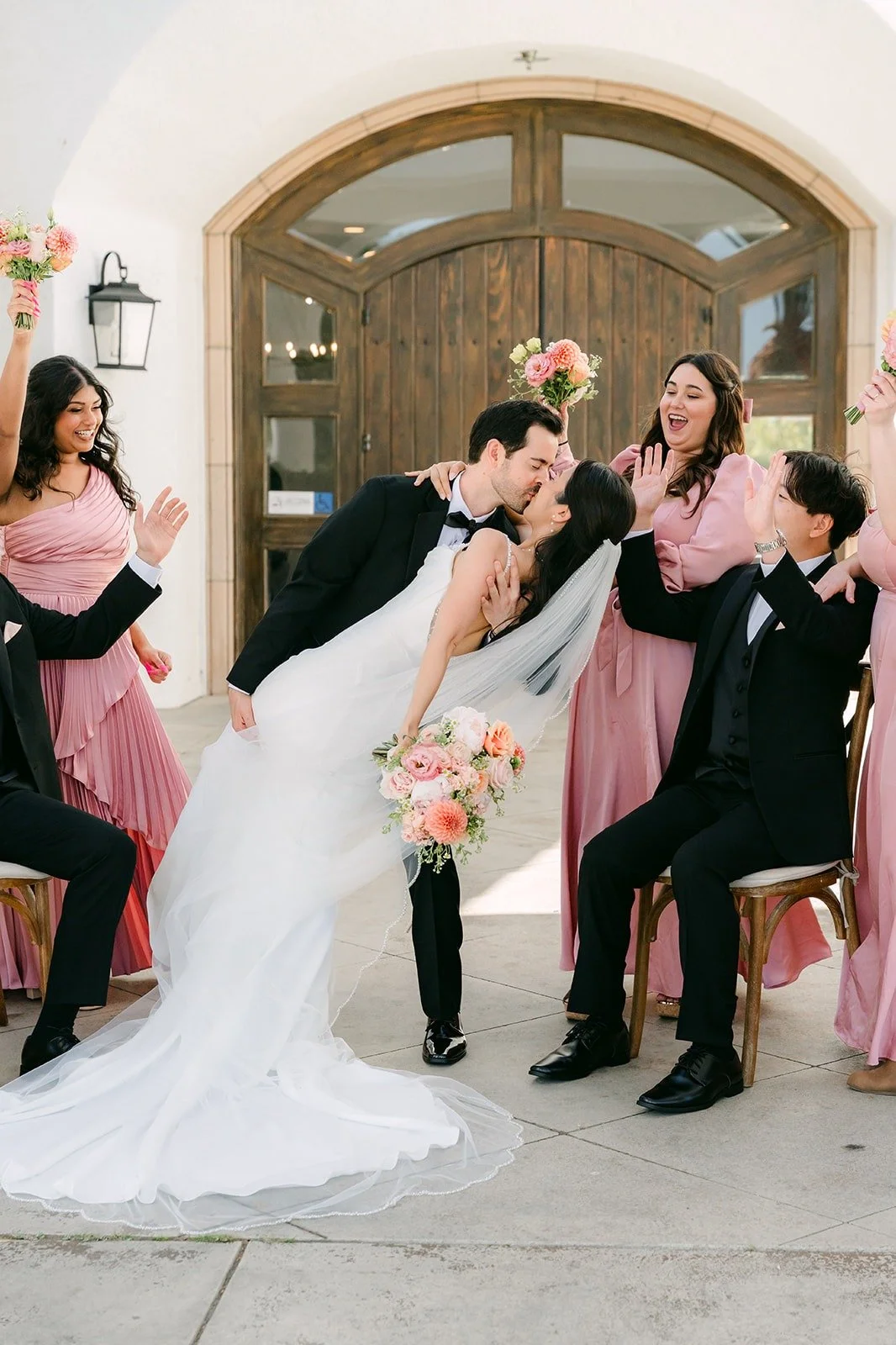 Kevin dipping Stephanie for a kiss while the wedding party cheers around them