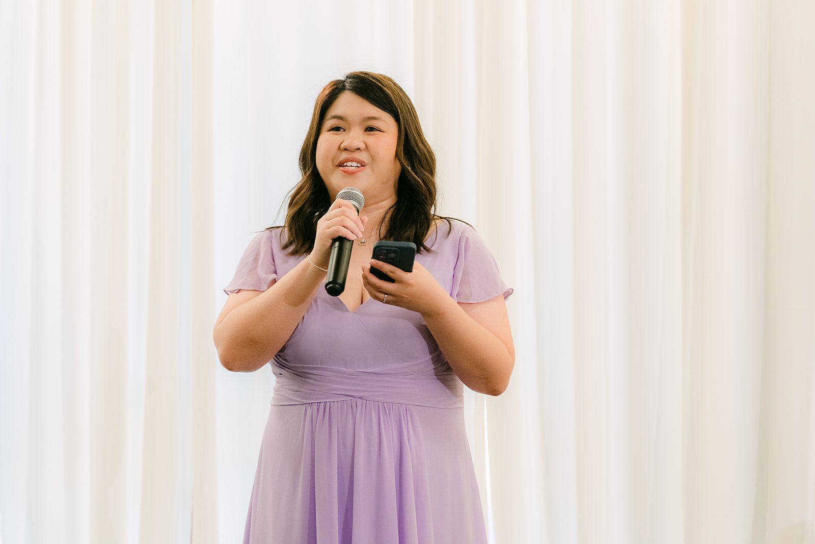 A friend in a lilac dress giving a speech at the reception.