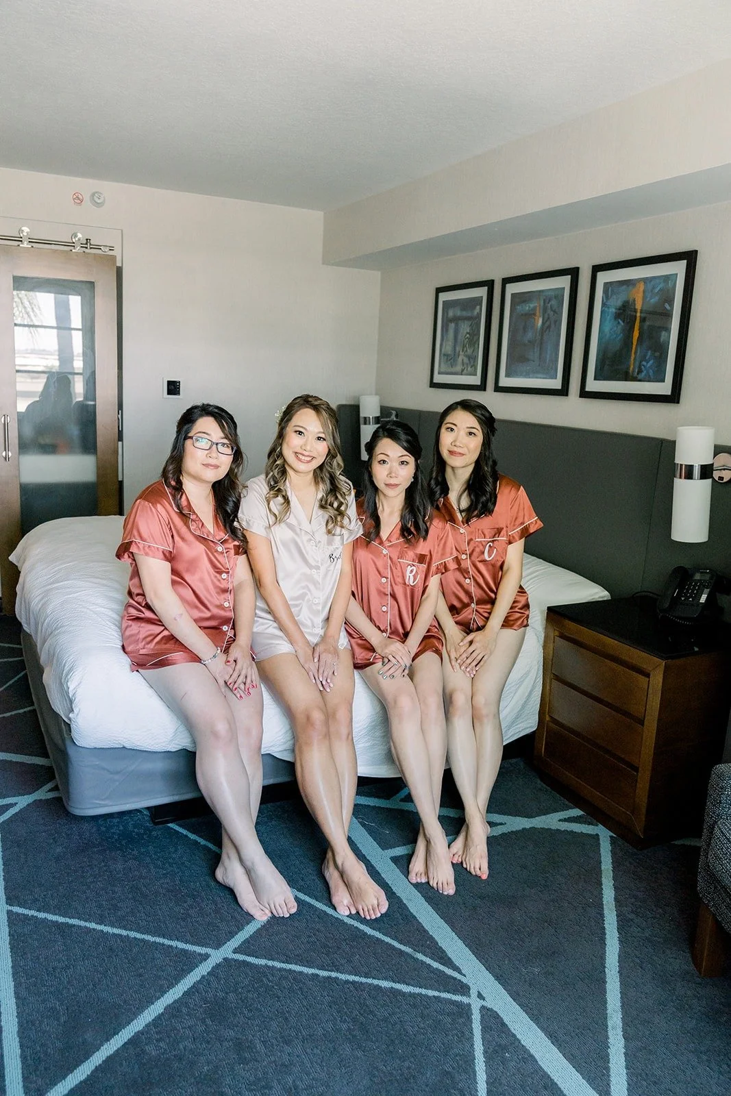 The bridesmaids lined up on the bed in matching robes