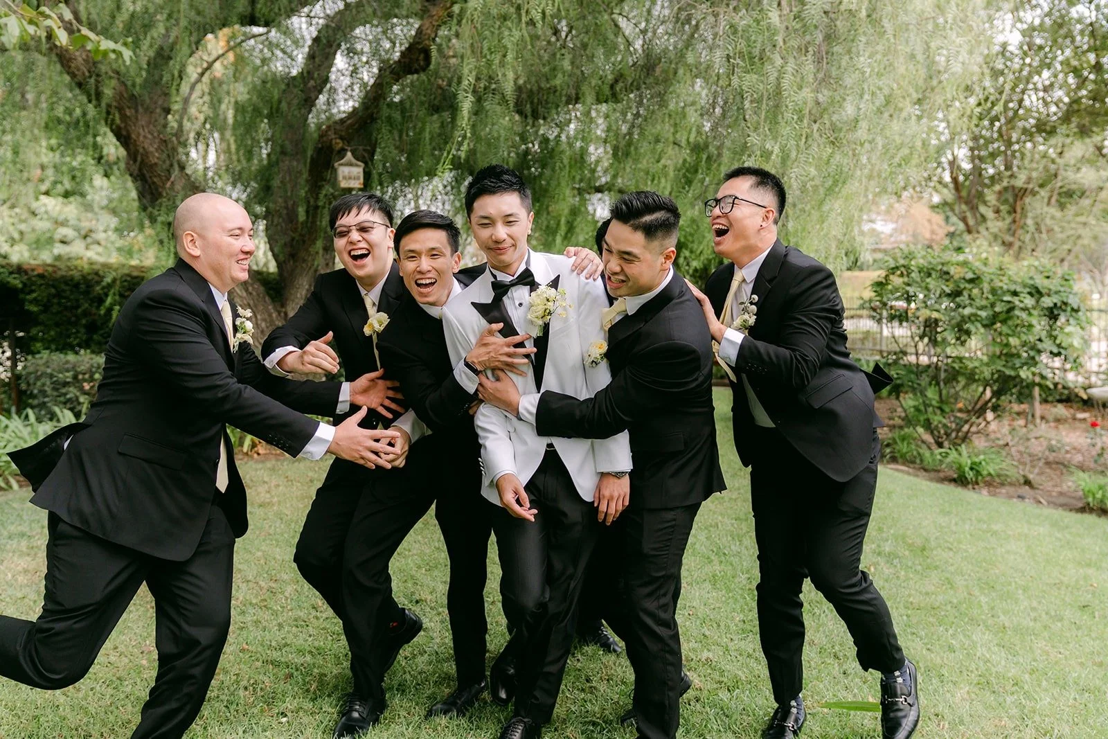 Groomsmen laughing and jumping around Ryan.