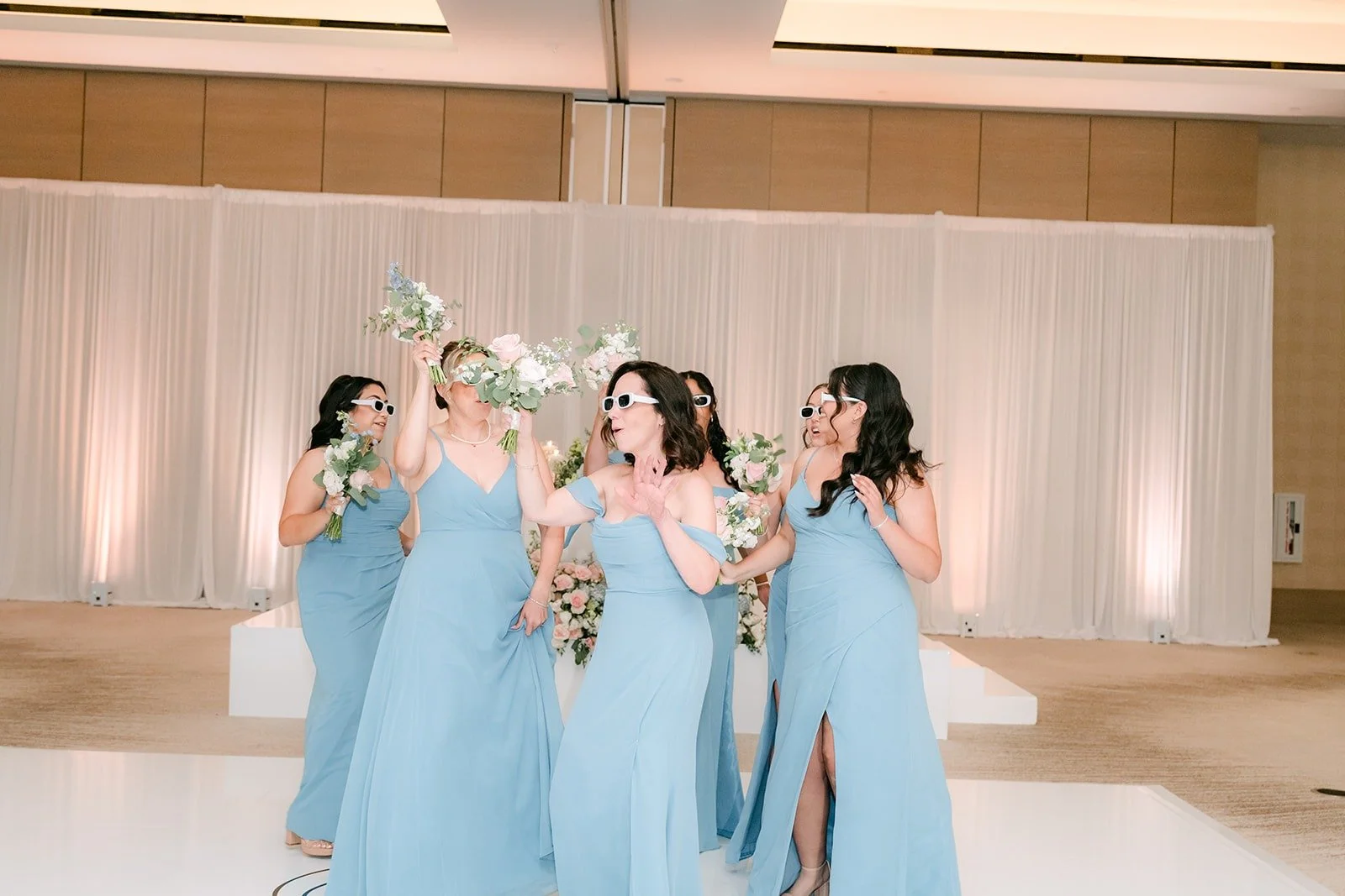 Bridesmaids wave their bouquets during the grand entrance