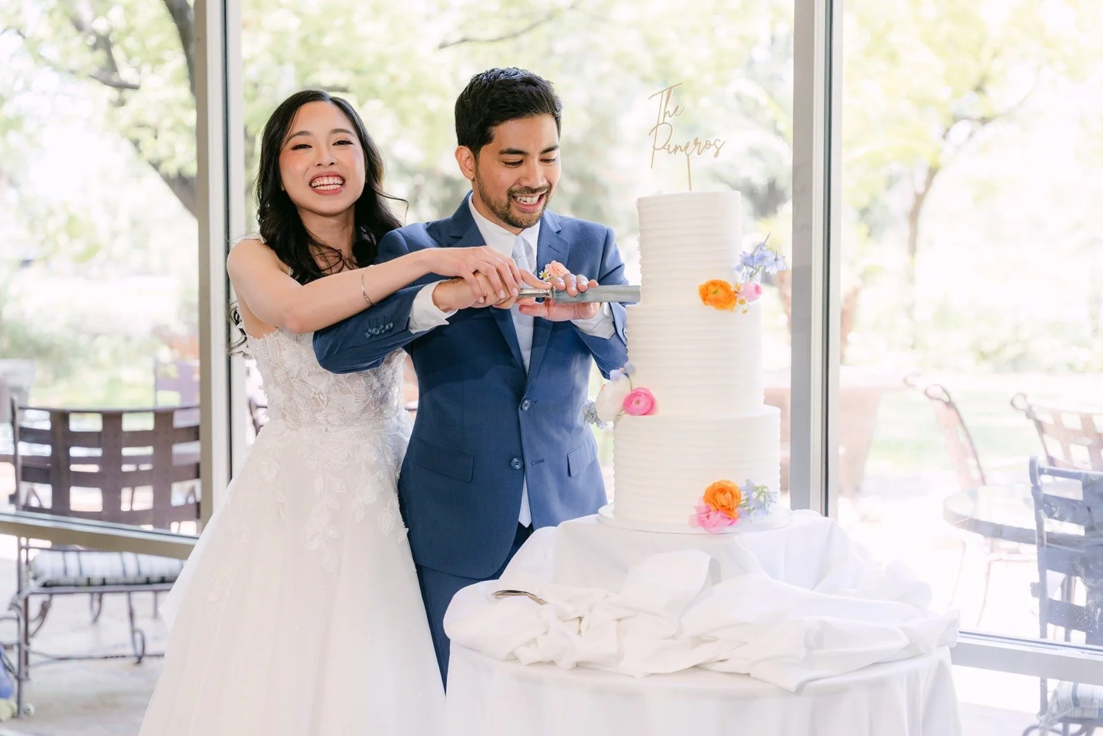 Natalie and Mark laughing as they cut their wedding cake