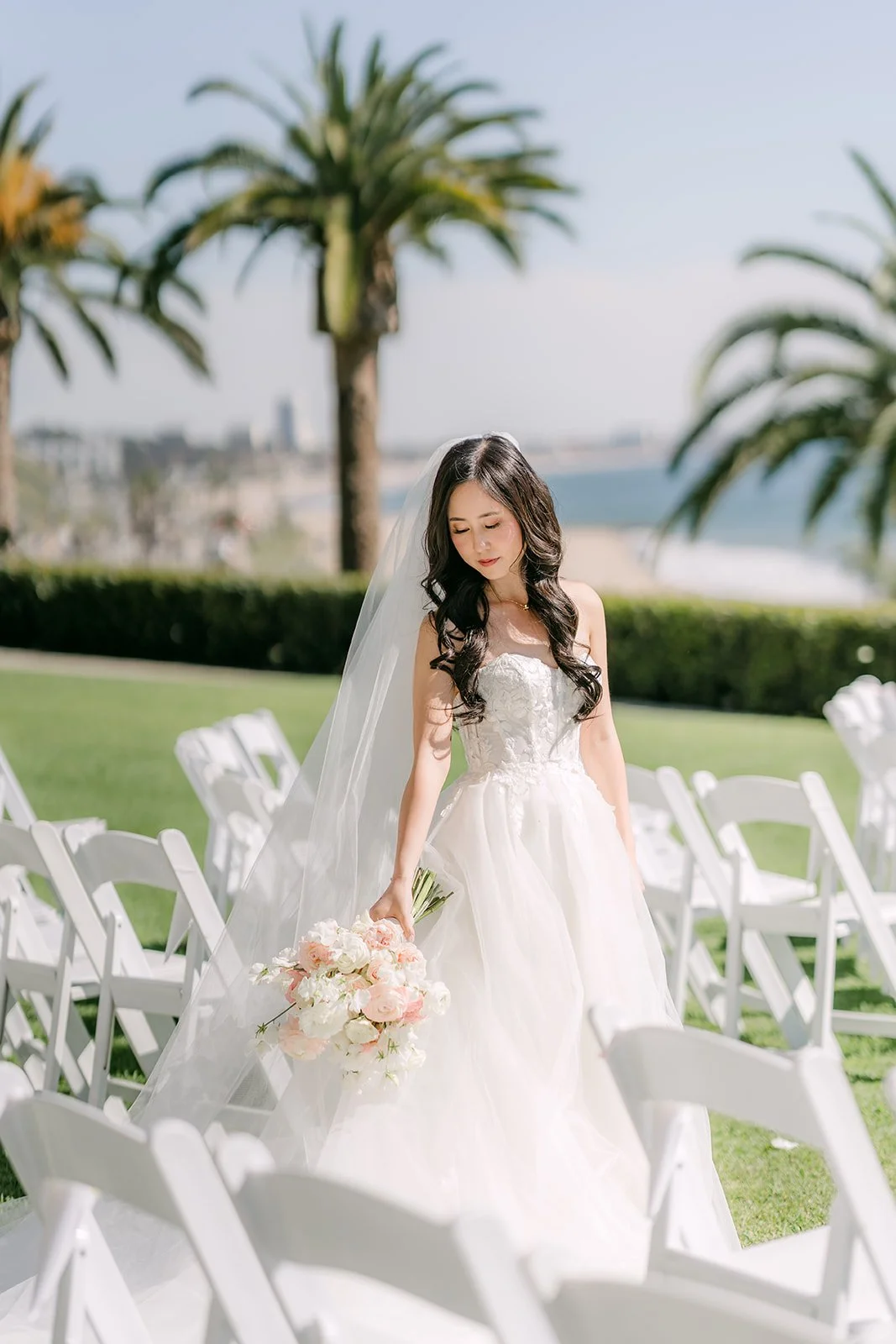 Bride walking down the aisle between rows of white chairs