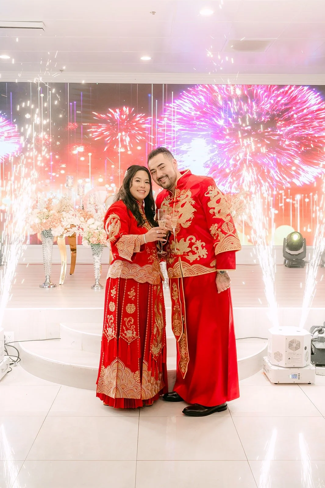 Amy and James posing with fireworks on the screen behind them