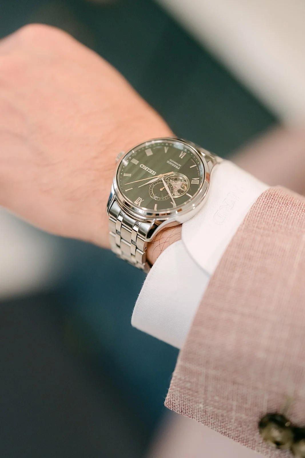Michael's watch and blush suit sleeve.