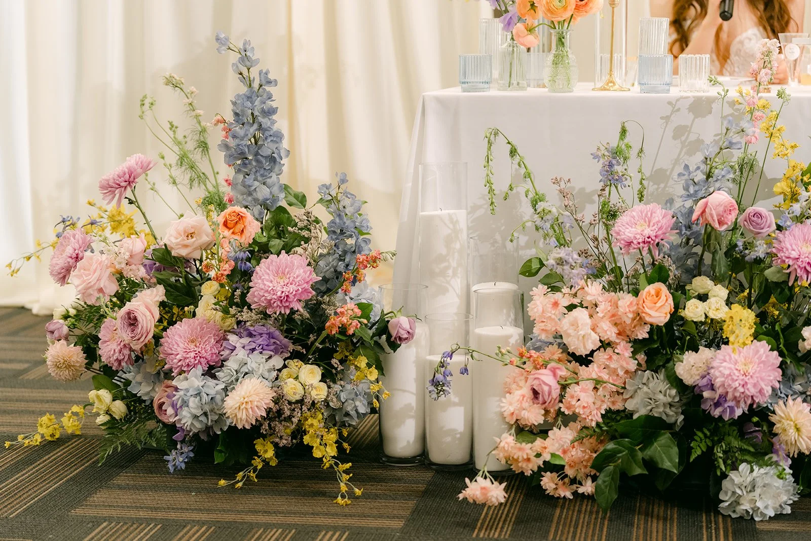 Christie and Christian at the sweetheart table framed by pastel florals.
