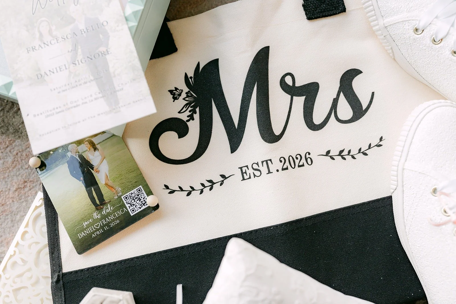 A black and white Mrs tote marked Est. 2026 beside an engagement photo