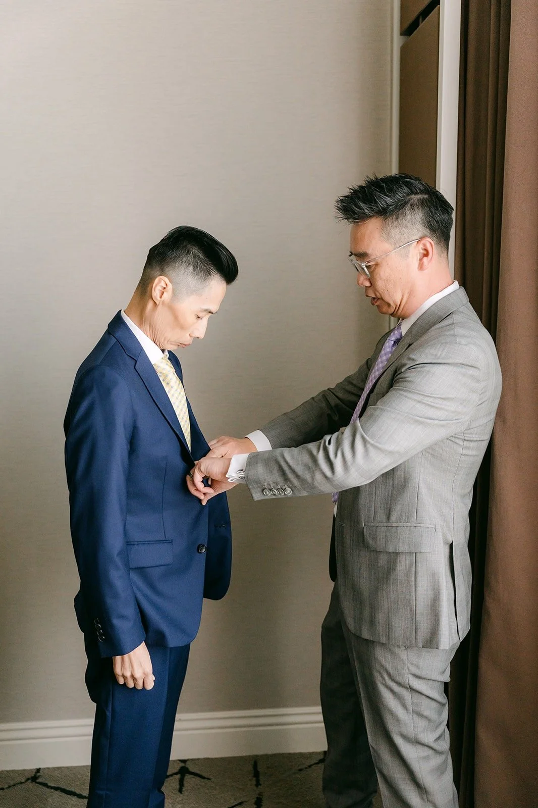 A groomsman helping Bobby with his jacket.
