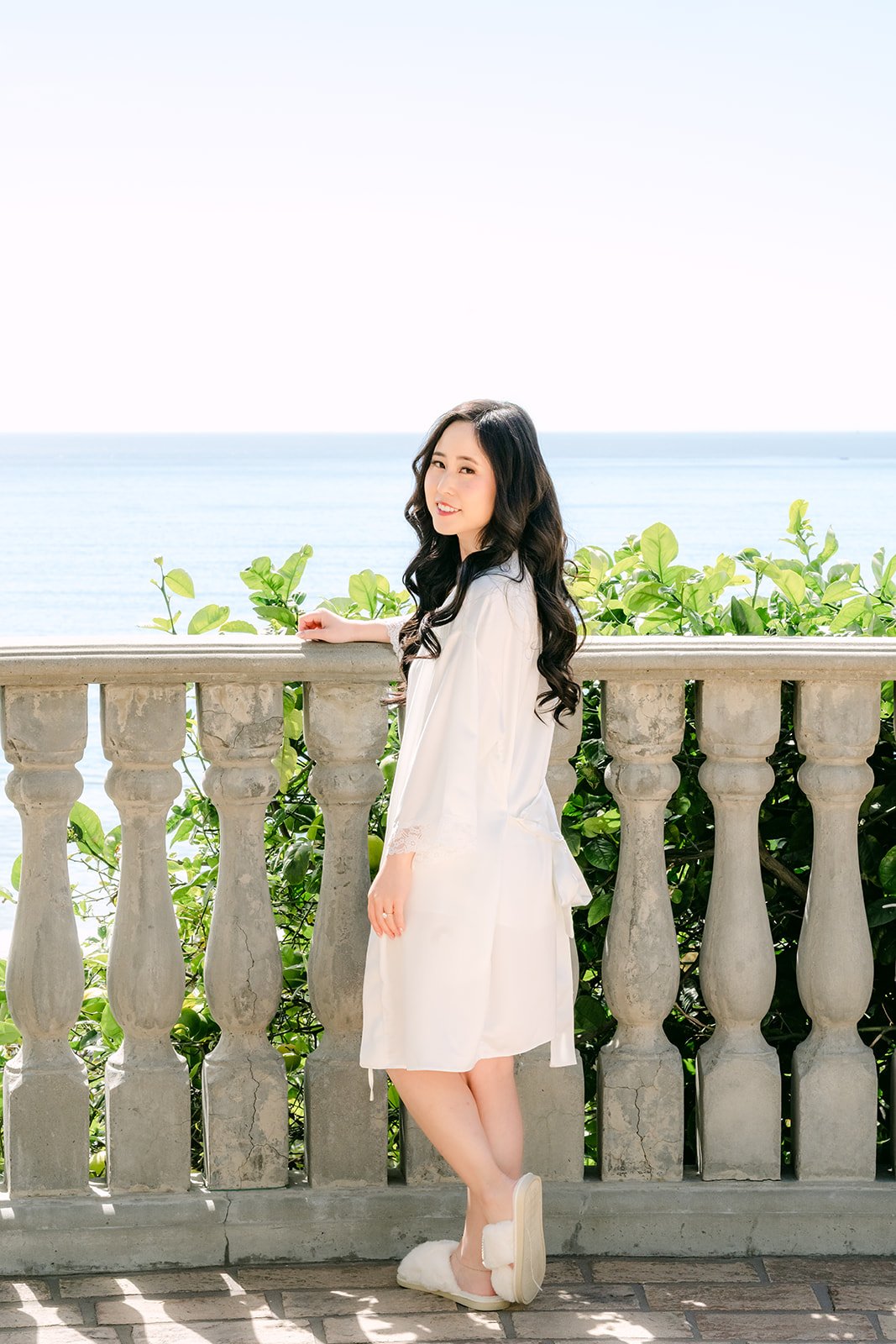 Kelley in a white robe on the ocean view balcony