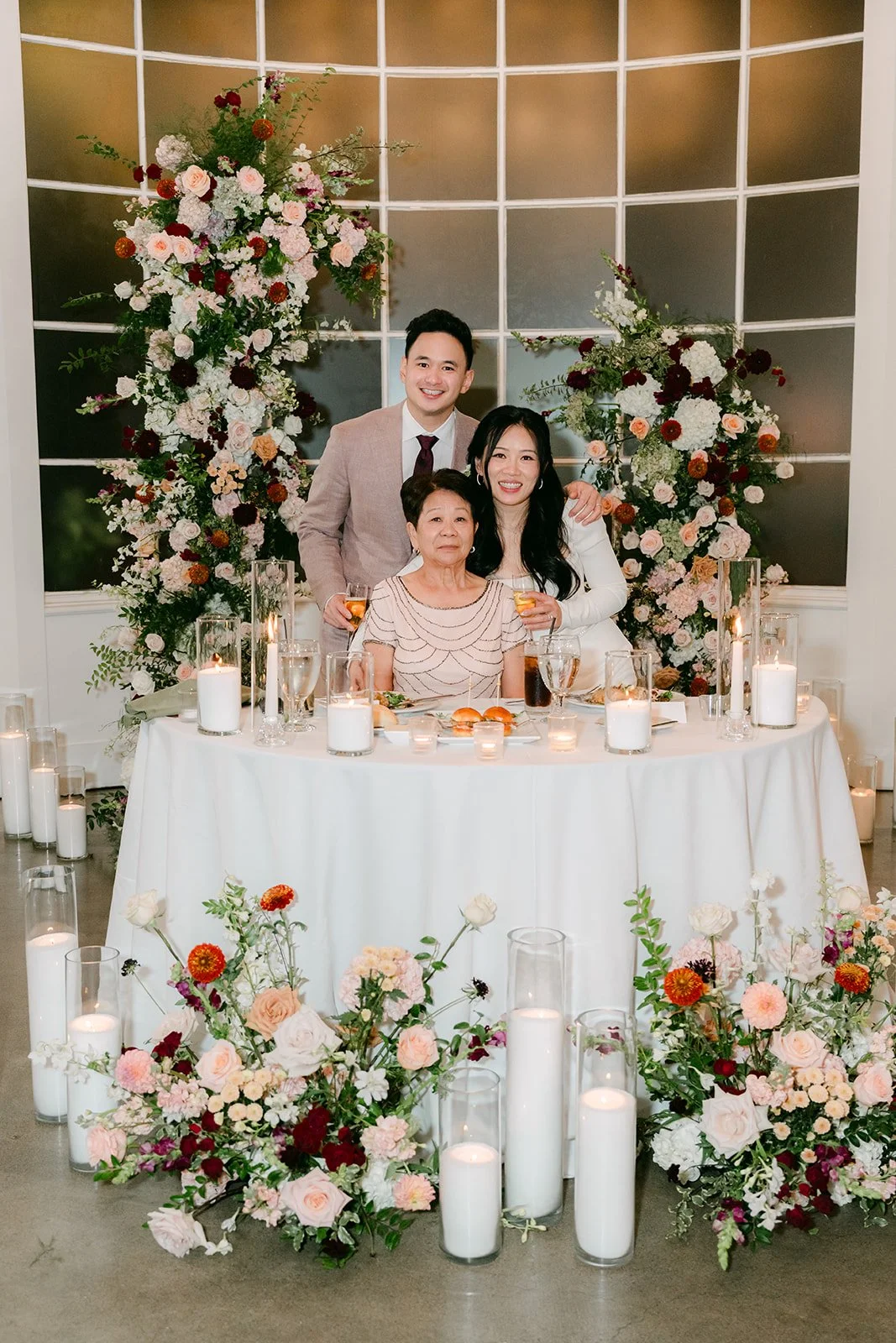 Denise and Michael at their sweetheart table behind the florals and candles.