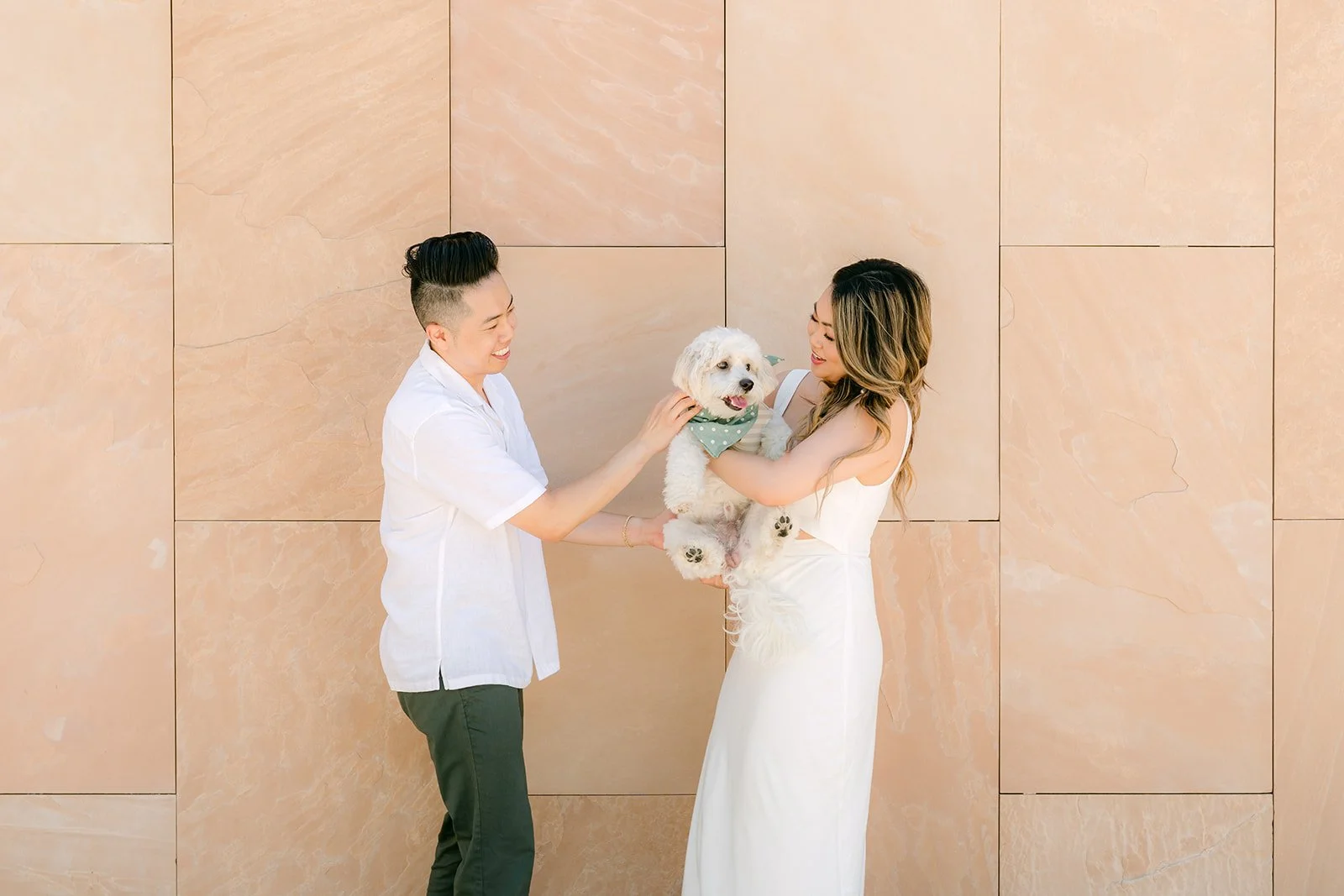 Alan and Stephanie hold Tofu up between them against the sandstone wall.