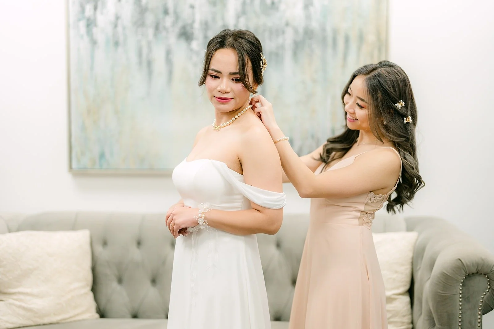 Ivy's maid of honor Linh helping her into her gown