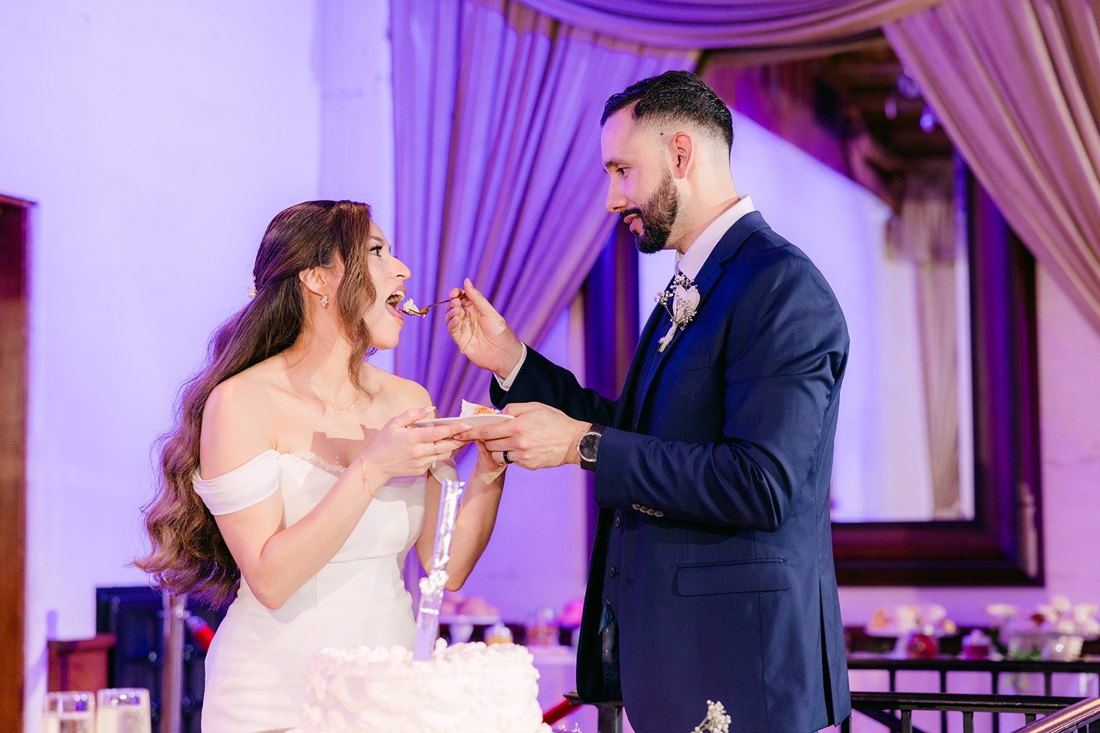 Mariana and Danny feeding each other cake, photographed by One and Only Production