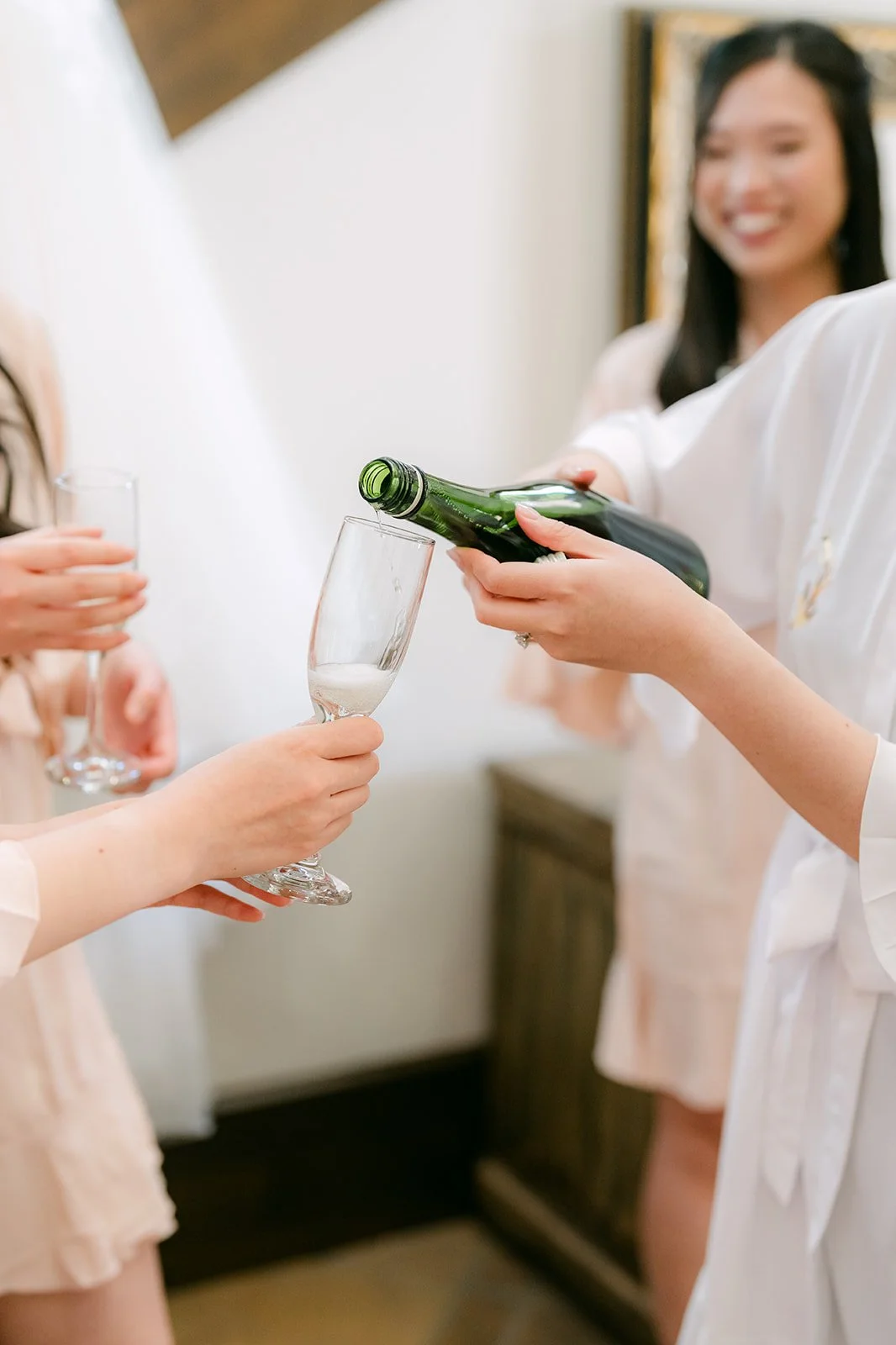 Champagne being poured into a glass while the bridesmaids look on