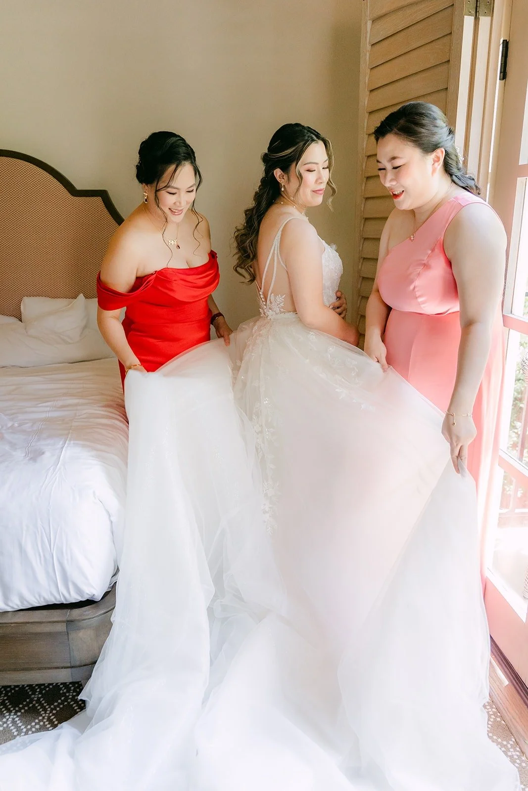 Joanne in her gown with two bridesmaids in red and pink in the suite