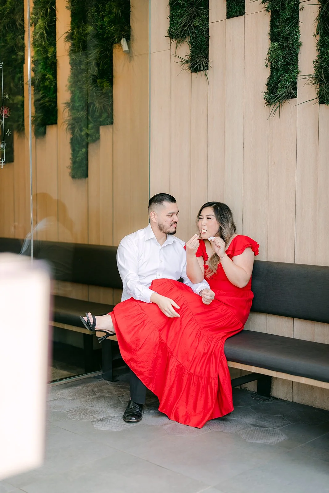 Linh and Ankush seated on the bench beneath hanging greenery.