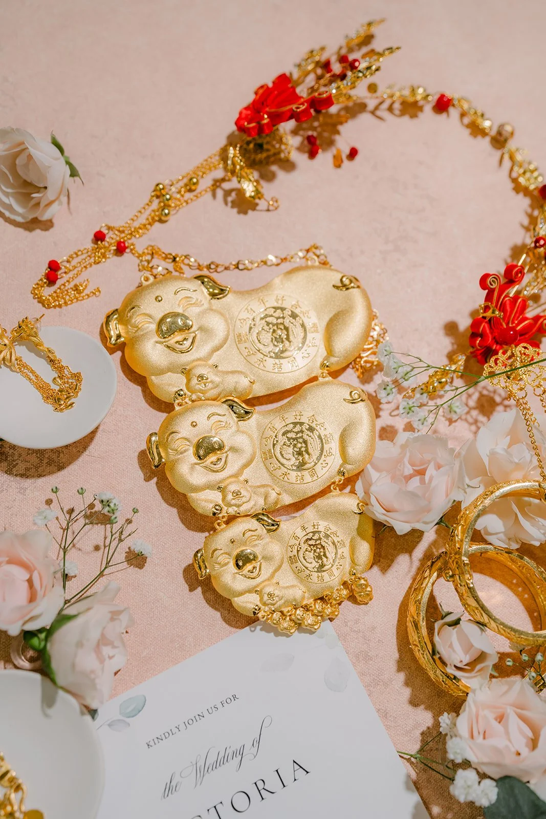 Gold bangles and pendants laid out on a floral flat lay.