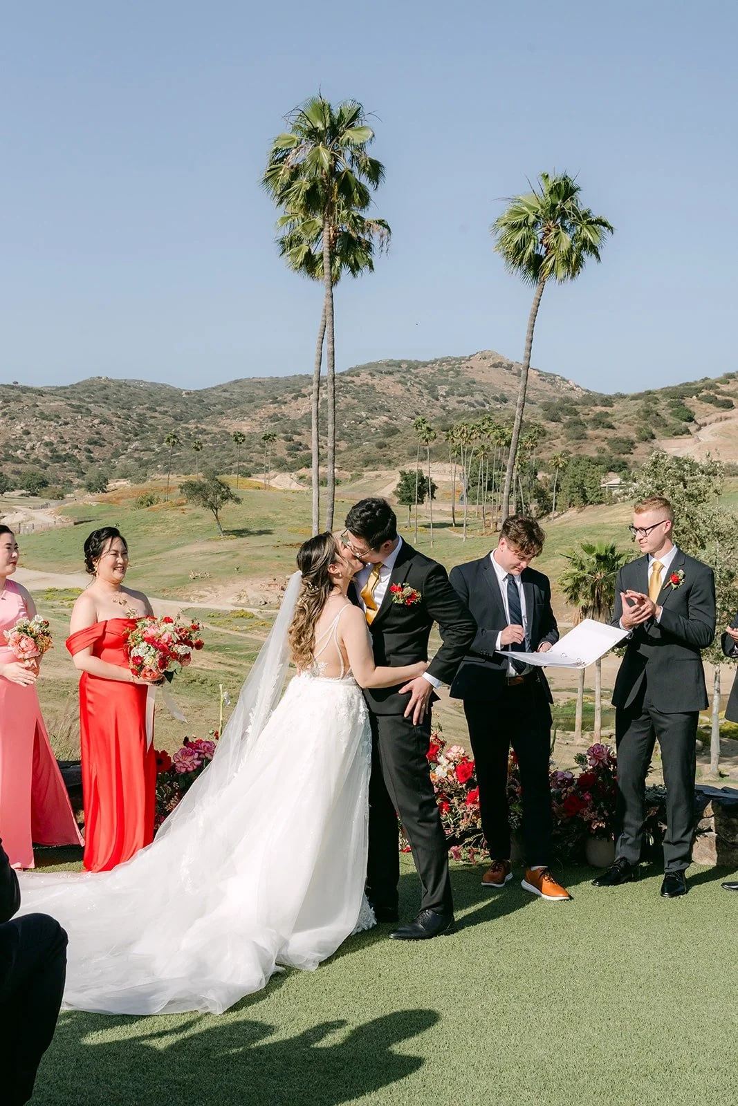 Joanne and Zach's first kiss with palm trees and hills behind them at the San Diego Zoo Safari Park