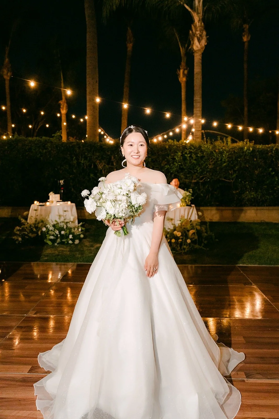 Amy holding her bouquet on the dance floor under the string lights