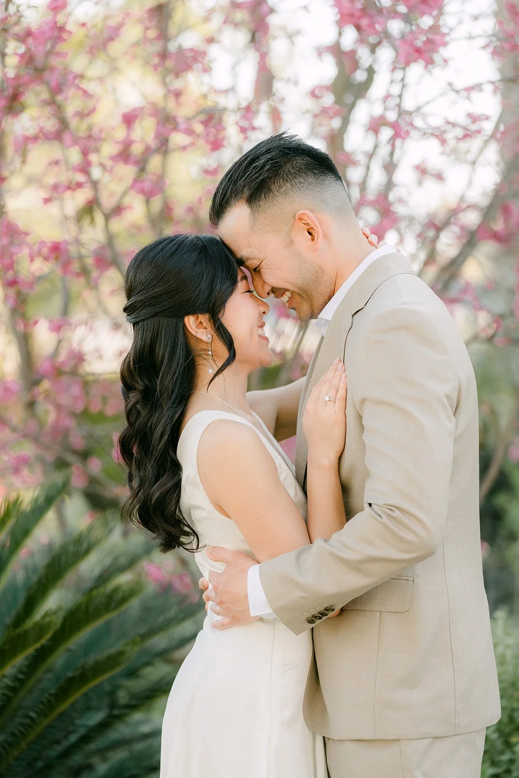 Kim and Vincent touching foreheads in front of the pink blooms.