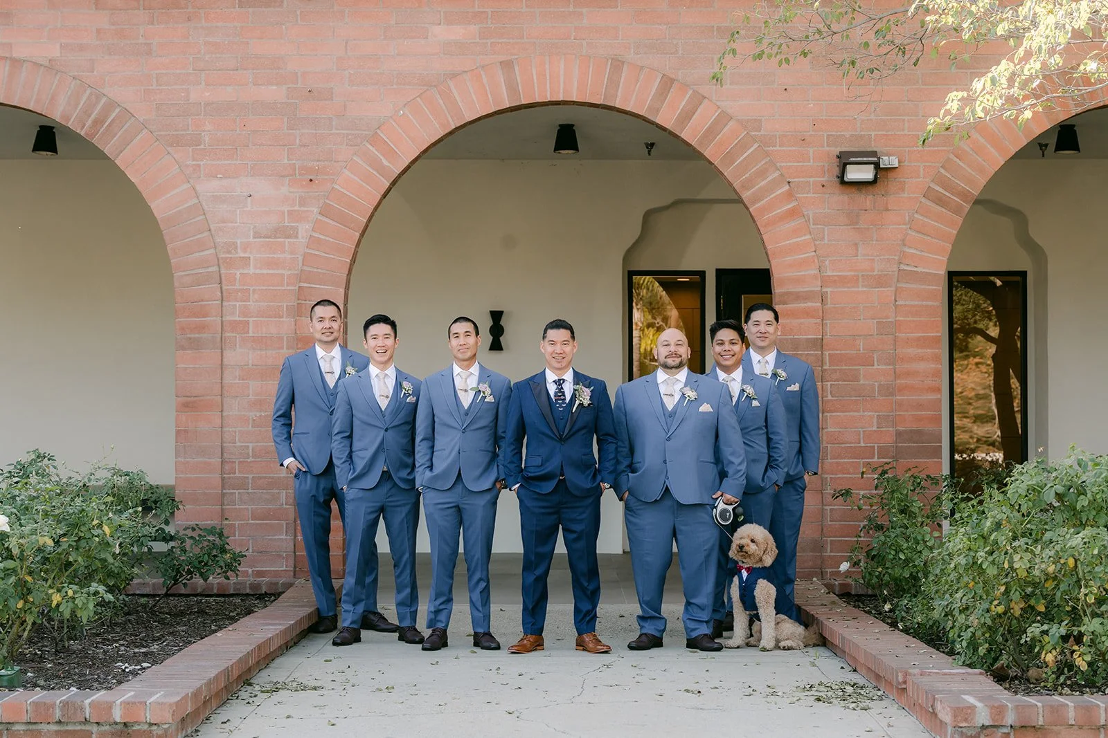 Michael and his groomsmen in navy suits in front of the brick arches.