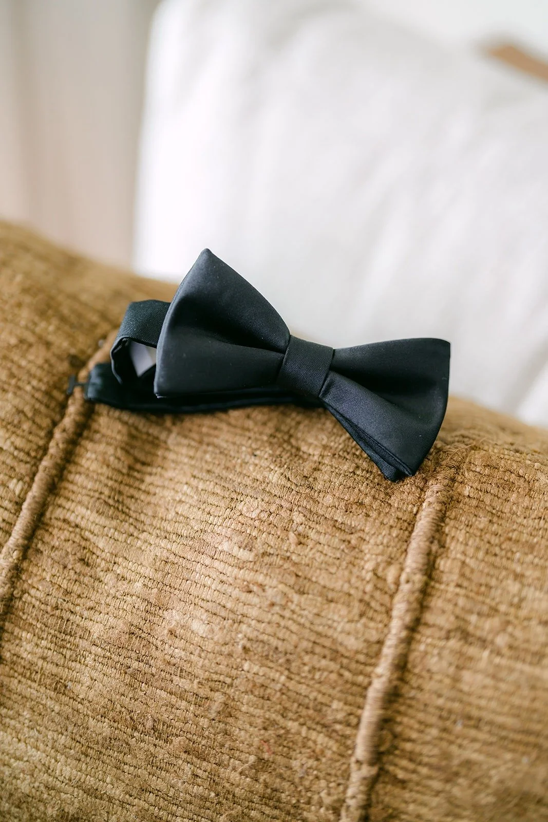 A black bow tie resting on a woven cushion