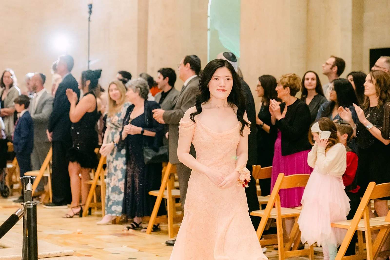 A bridesmaid in blush during the ceremony, photographed by One and Only Production