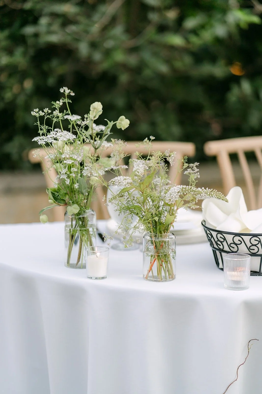 A round reception table set with wildflowers under the trees