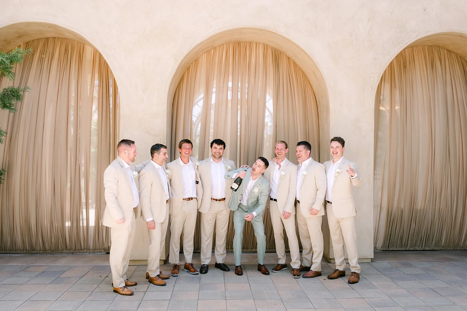 Groom and groomsmen lined up in front of the curtained loggia arches