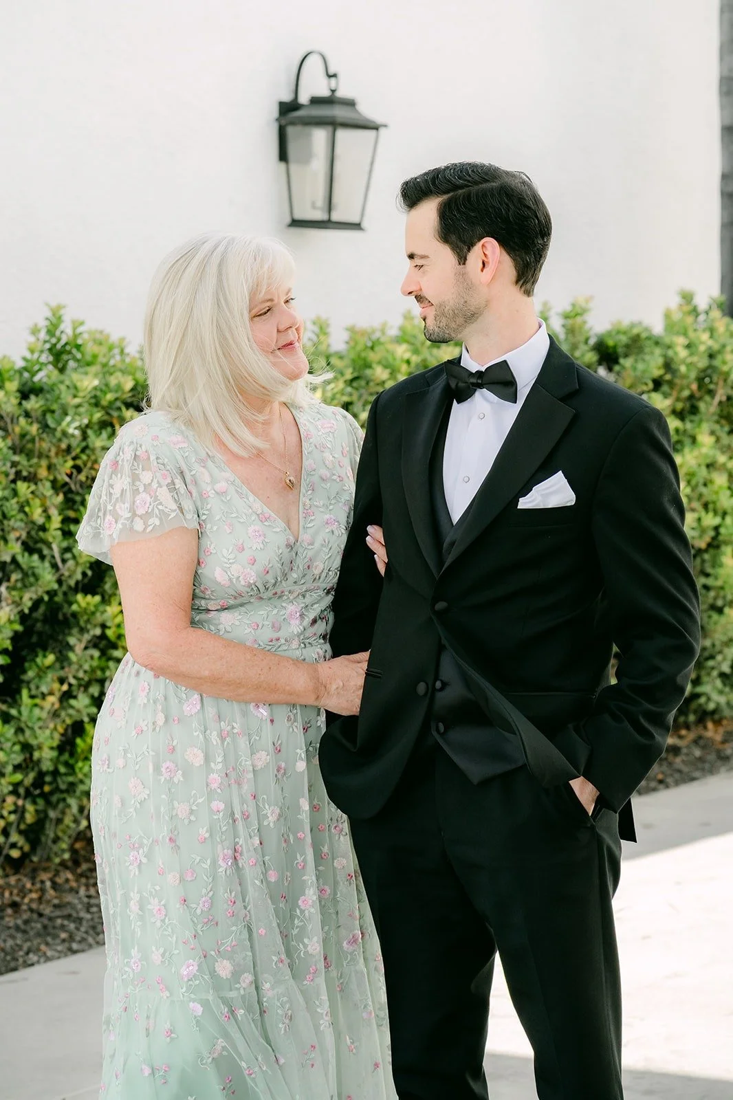 Kevin and his mom smiling together in front of the hedge
