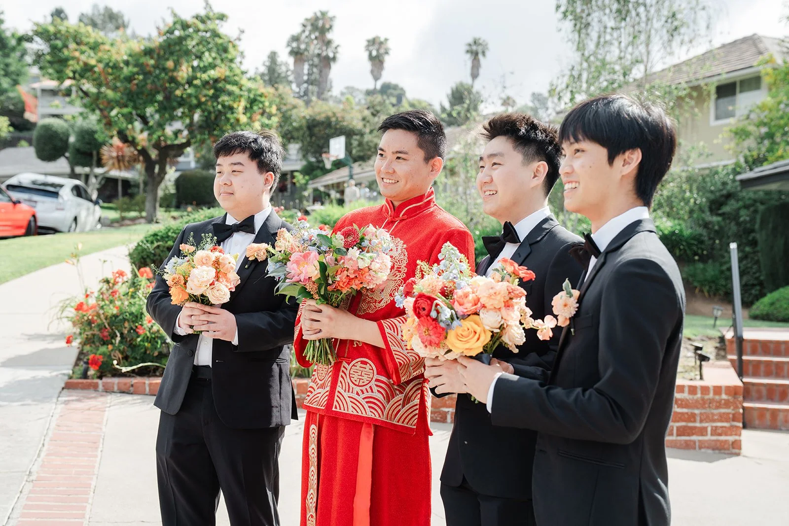 Henrik and his groomsmen holding gifts and the bouquet on the front lawn.