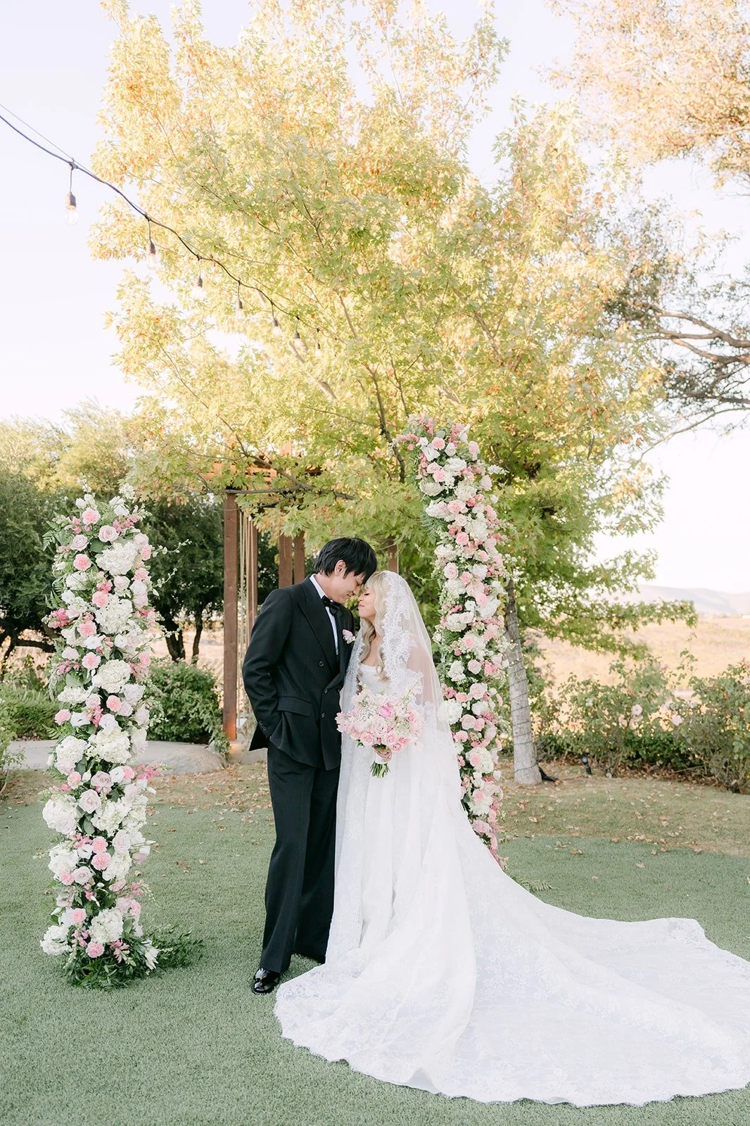 Konitha and Job between the floral columns on the ceremony lawn