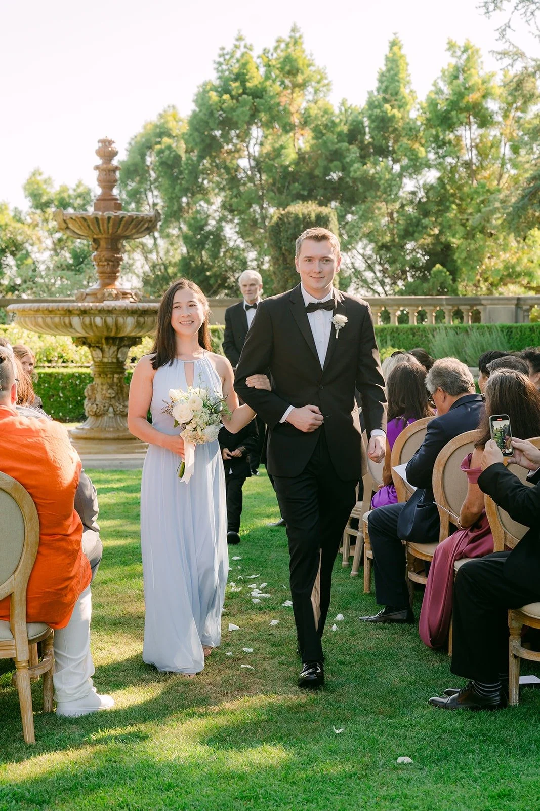 Brianna and Nik's wedding party heading up the aisle past cheering guests, photographed by One and Only Production