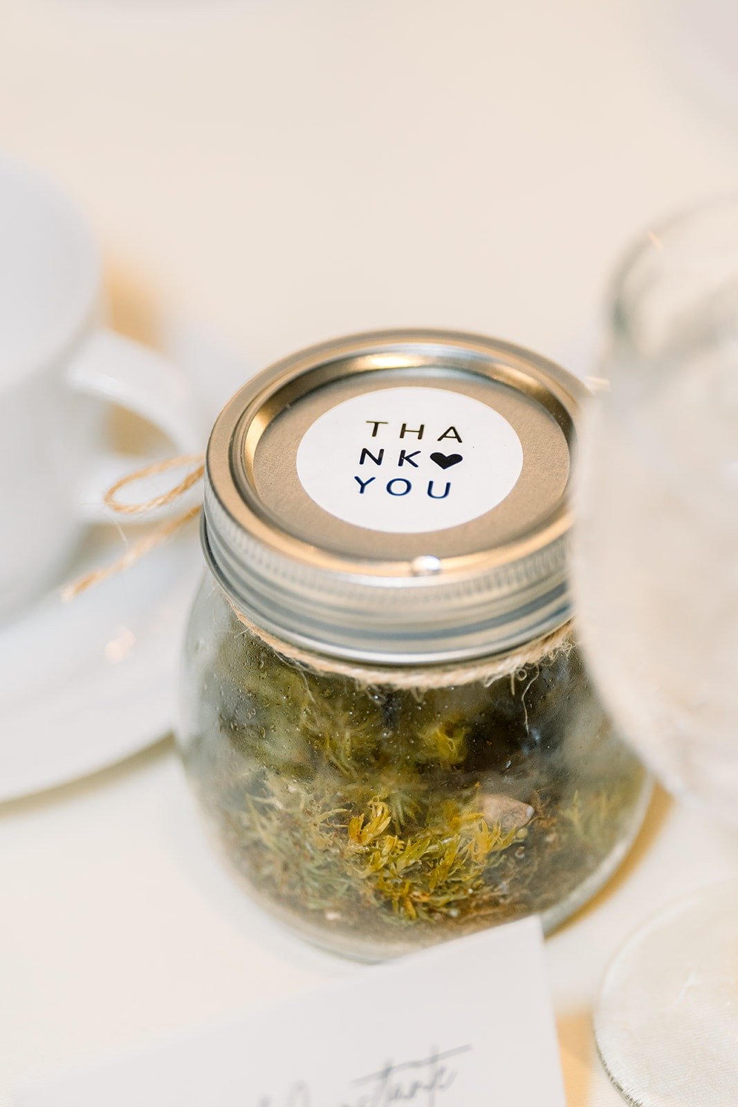 A moss terrarium favor jar with a thank you lid