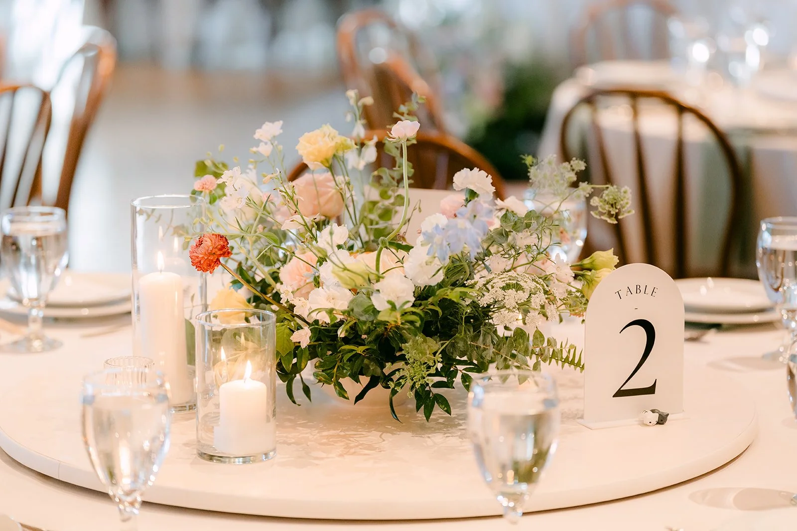 Centerpiece of pastel florals and candles beside table number two