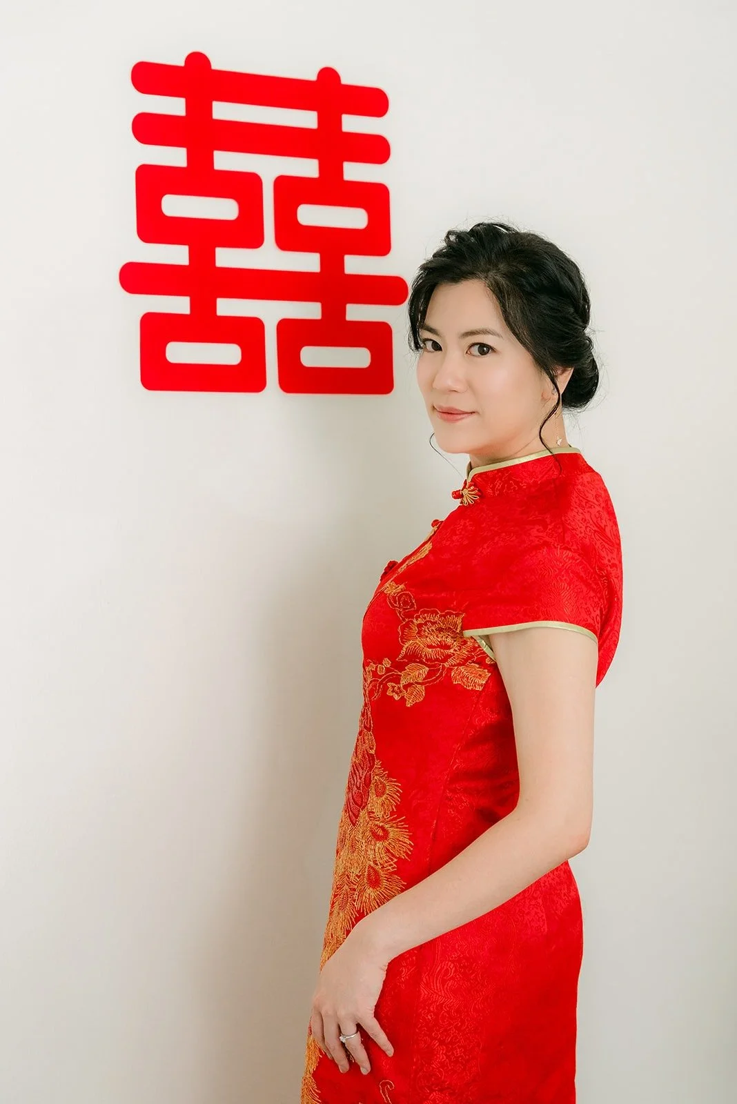 Eunice in profile beside a red double happiness sign on the wall