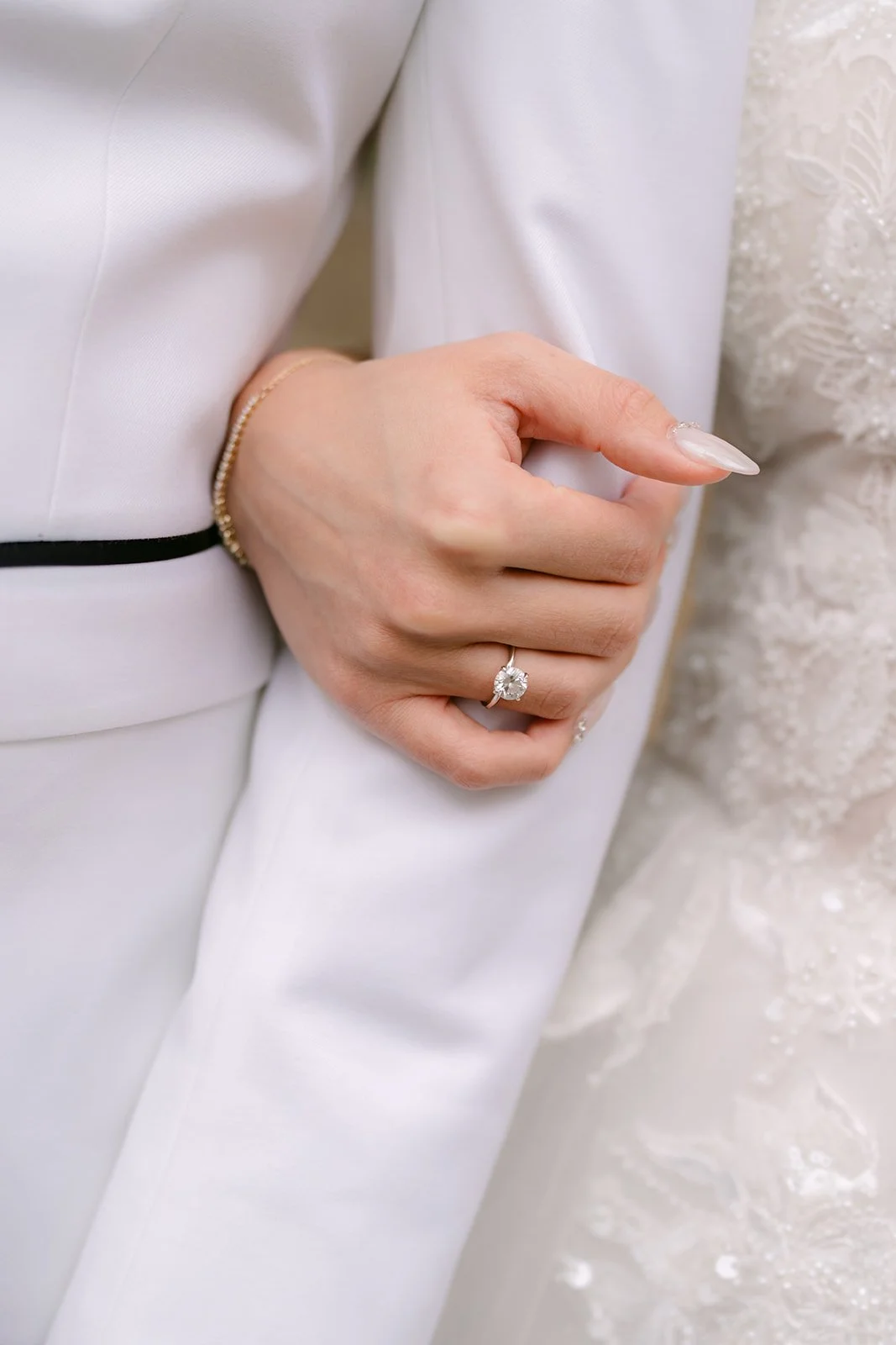 Jenny's hand and ring resting on Ryan's white sleeve.