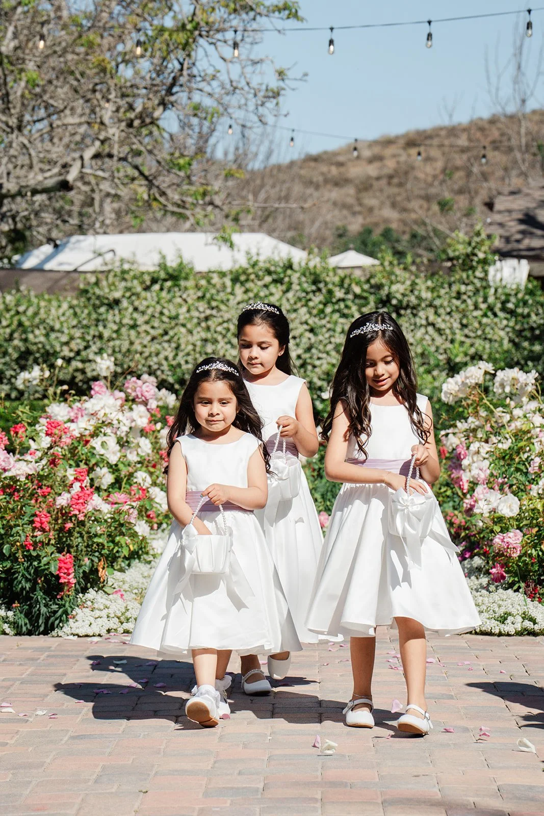 Flower girls in white dresses walking down the aisle