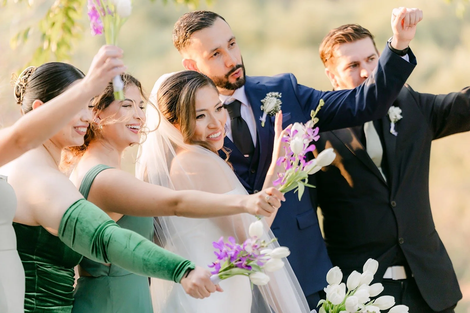 The wedding party cheering with bouquets in the air