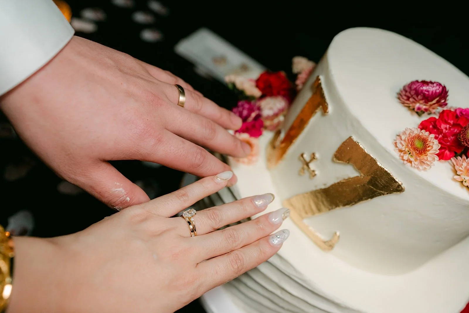 Joanne and Zach's hands cutting the cake together