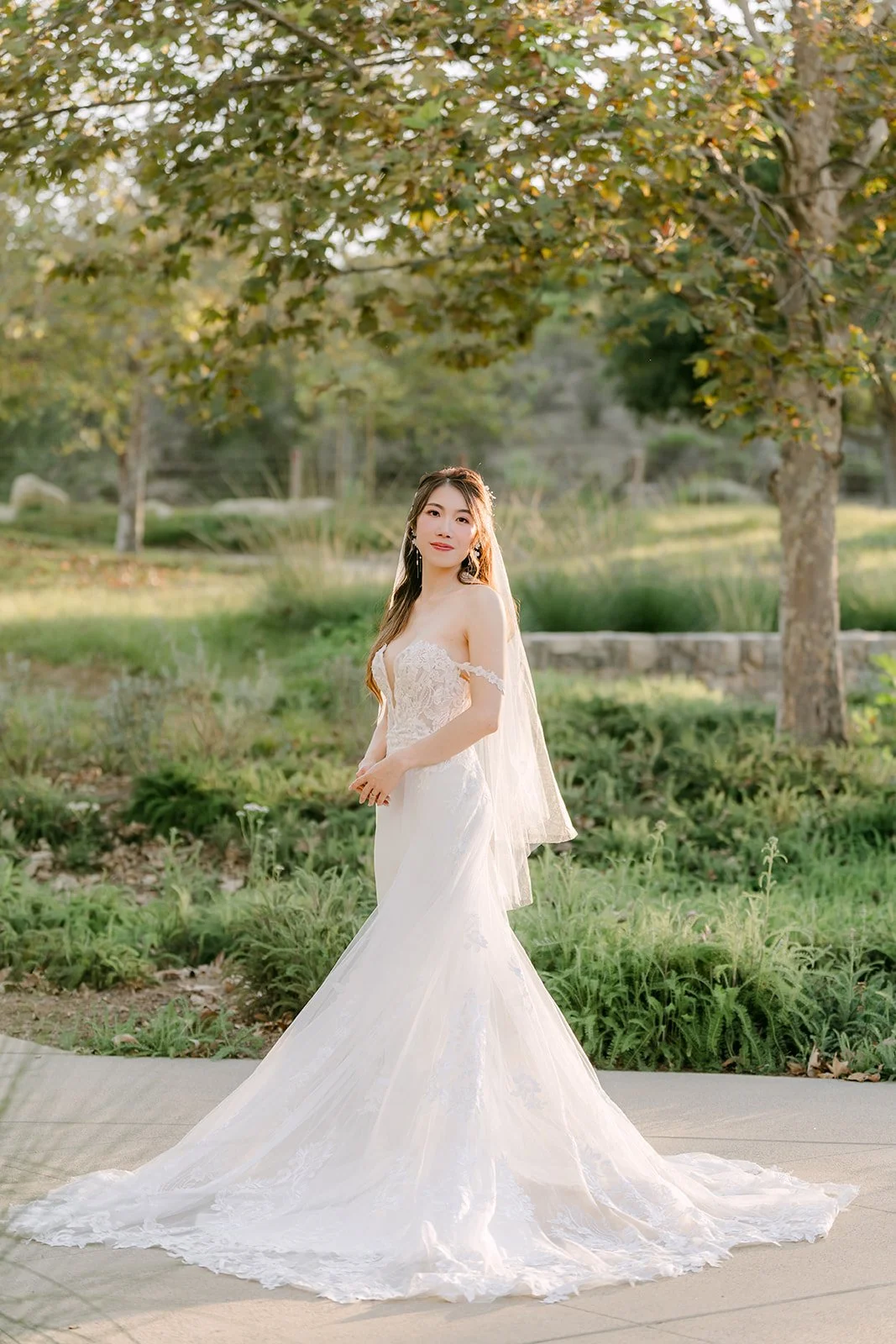 Christie in her gown and veil on the path among the trees.