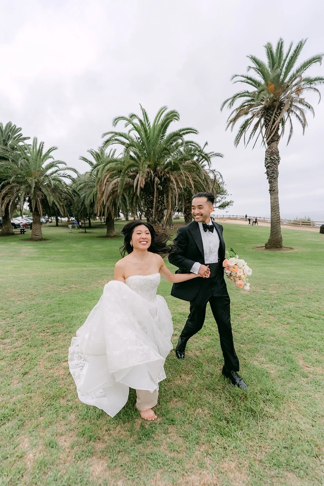 Kim and Vincent walking across the lawn under the palm trees at Point Vicente Interpretive Center