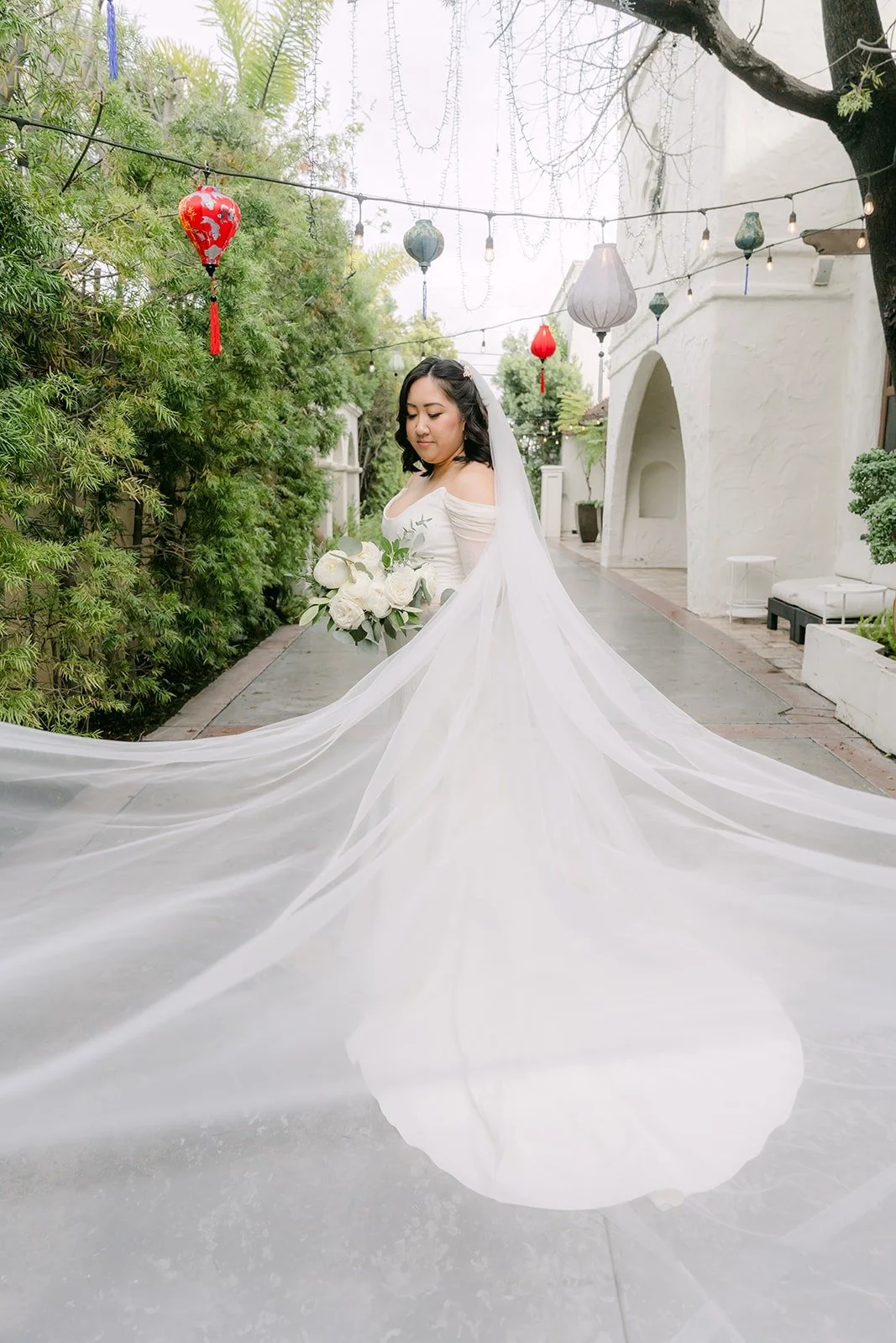 Vivian's cathedral veil spread across the courtyard path, photographed by One and Only Production