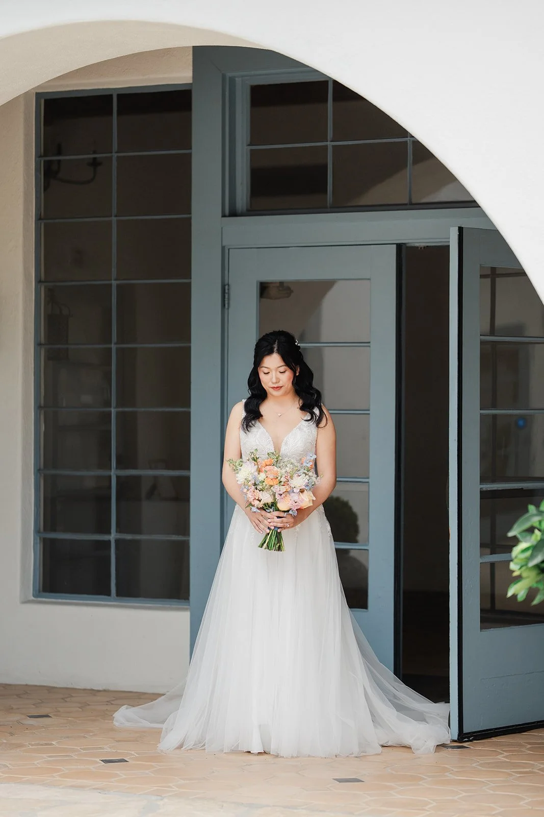 Bride walking through the courtyard arch toward the groom