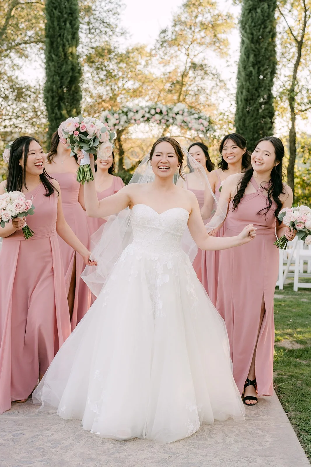 Victoria laughing with her bridesmaids in dusty rose gowns